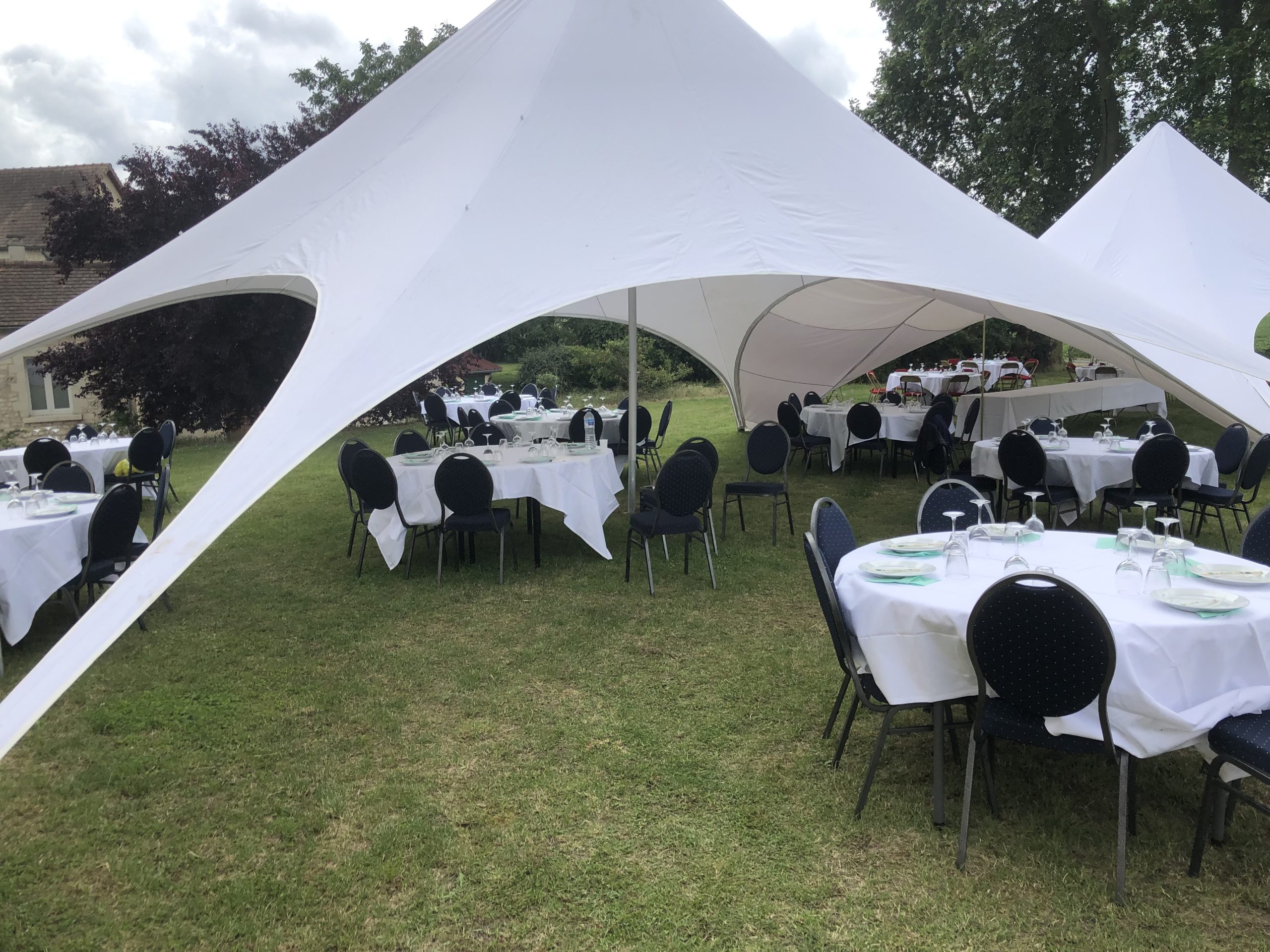 Tonnelle de réception installée pour un repas d’événement au Domaine La Rimbertière près de Poitiers avec tables rondes et chaises